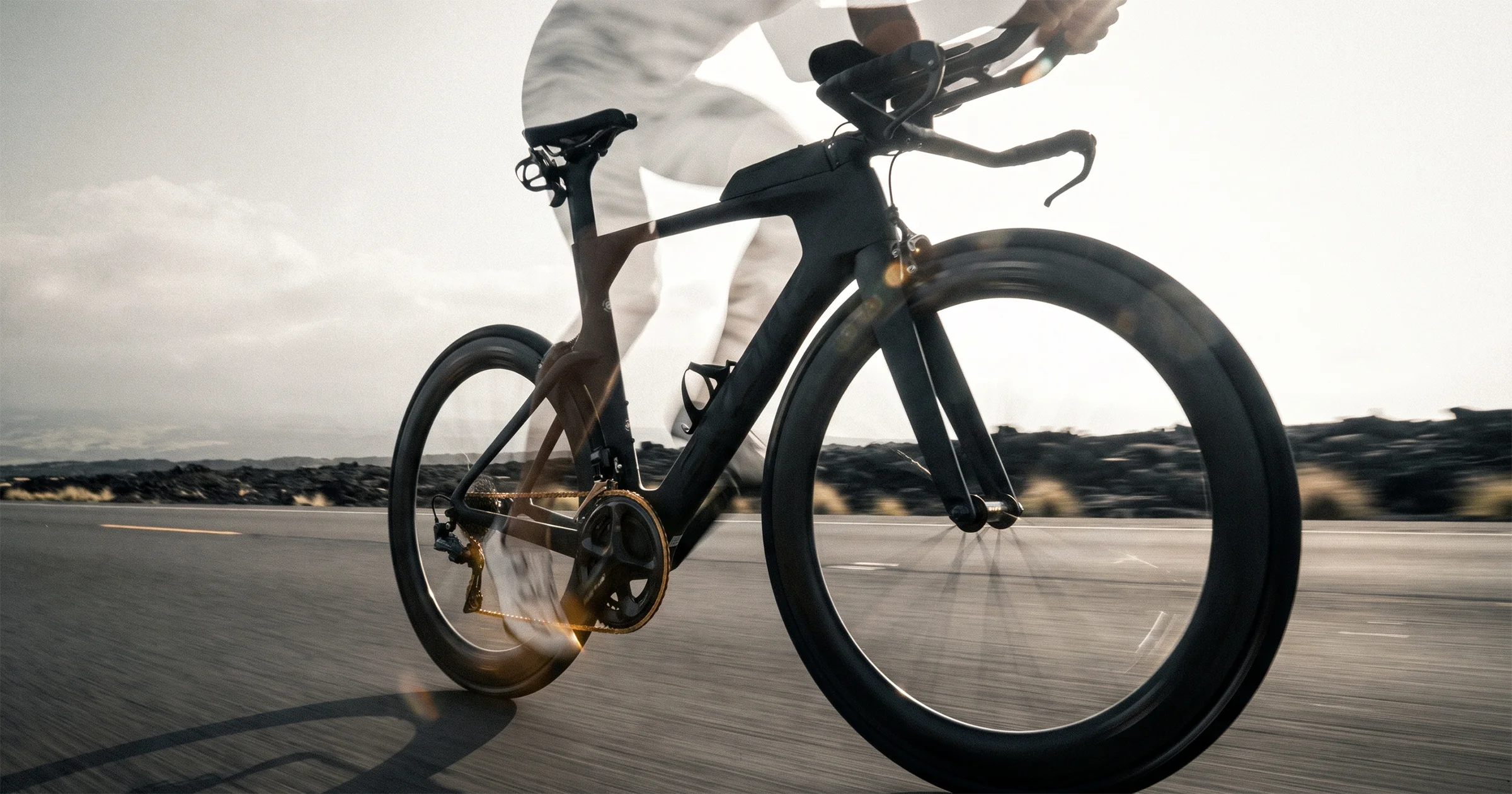 A state-of-the-art carbon time-trial bike powering at speed down the Queen K Highway in Kona; the rider is a translucent heat-haze ghost — present only as shimmering air — the machine is real, but the legs driving it were never built.
